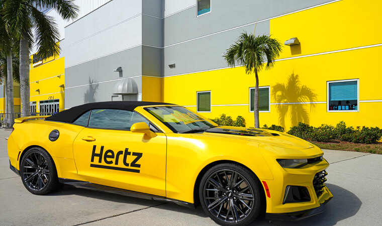 Yellow hertz car parked in front of hertz office