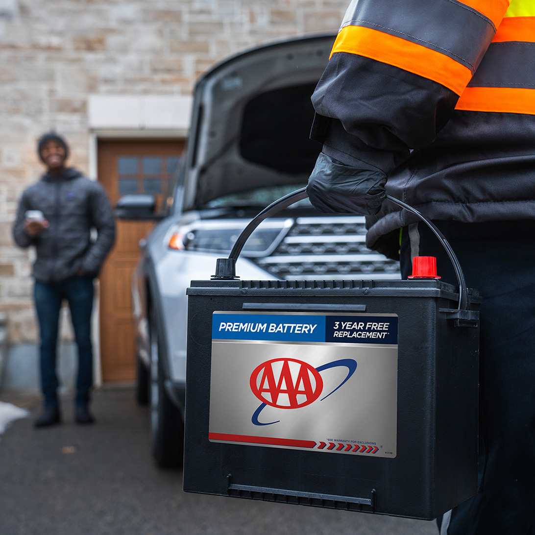 AAA service member delivering car battery to AAA member